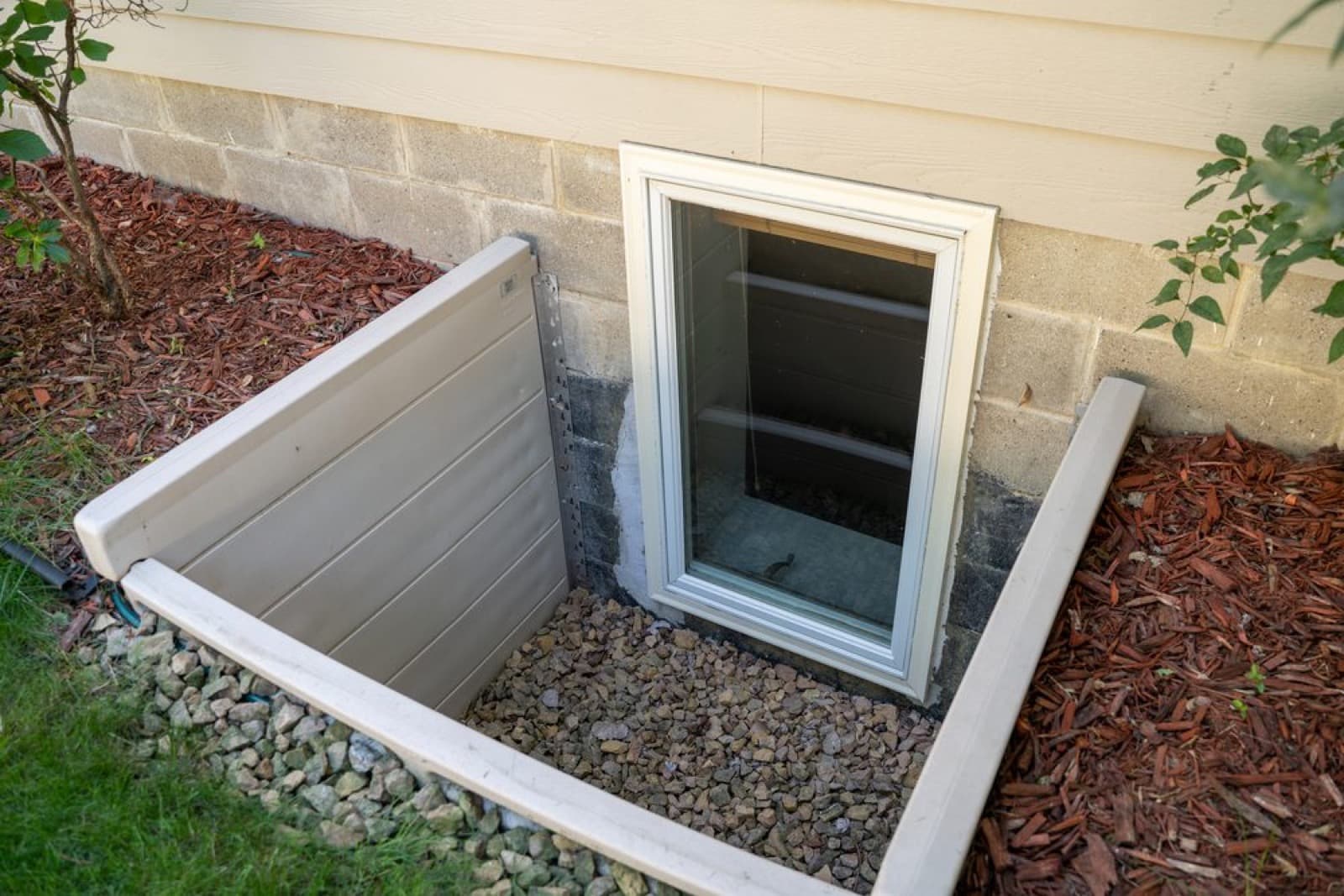 Basement window well next to a foundation wall