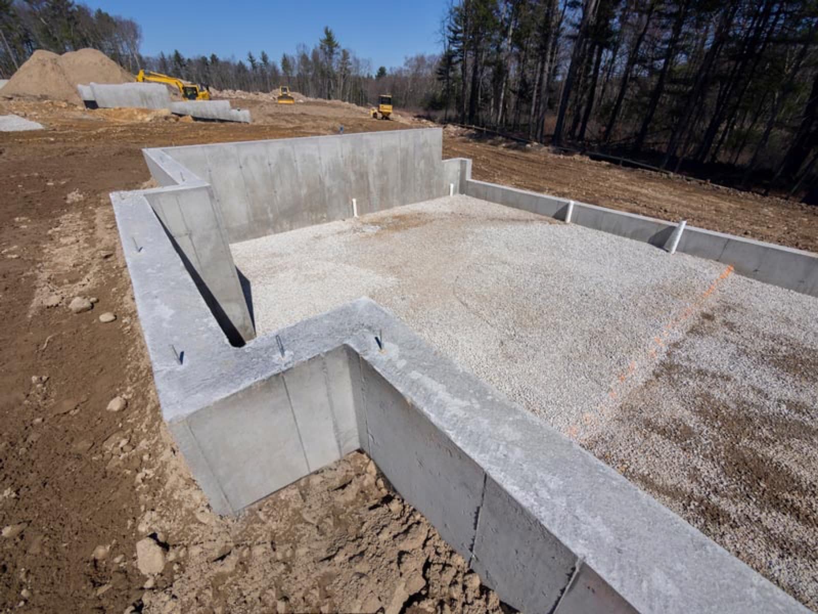 Real photo of a poured concrete foundation footing forming a basement outline at a large new home construction site