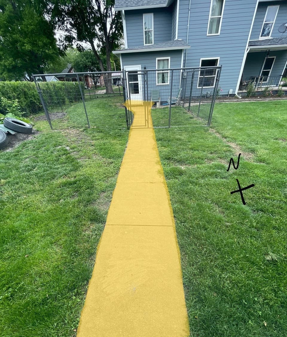 A yellow concrete lifting pad is visible in a residential backyard, appearing to be part of a polylift concrete repair installation with a fenced enclosure in the background.
