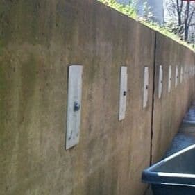 Exterior concrete wall with several wall anchors installed to repair bowing wall.