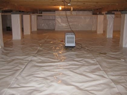 Crawl space after encapsulation with white vapor barrier and dehumidifier for moisture control