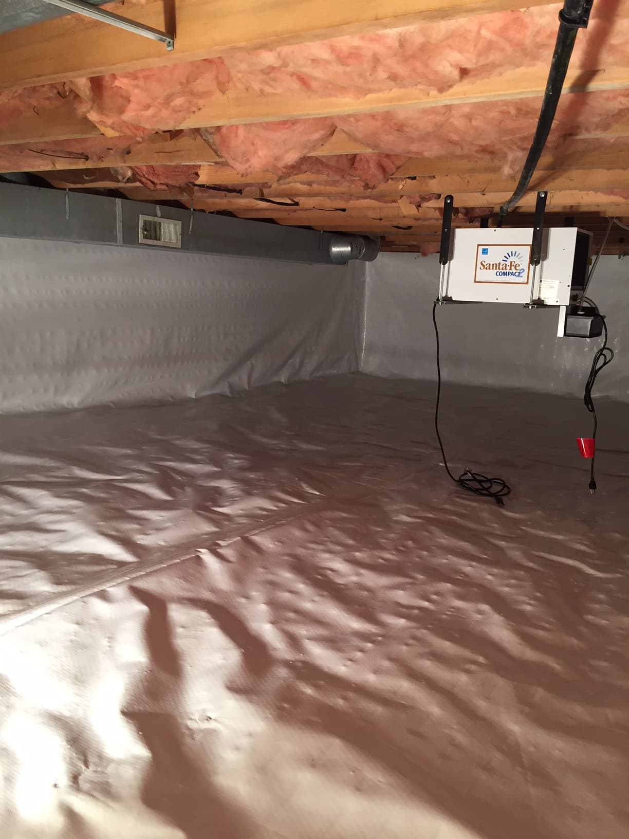 Crawl space after encapsulation with white vapor barrier and Santa Fe Compact dehumidifier