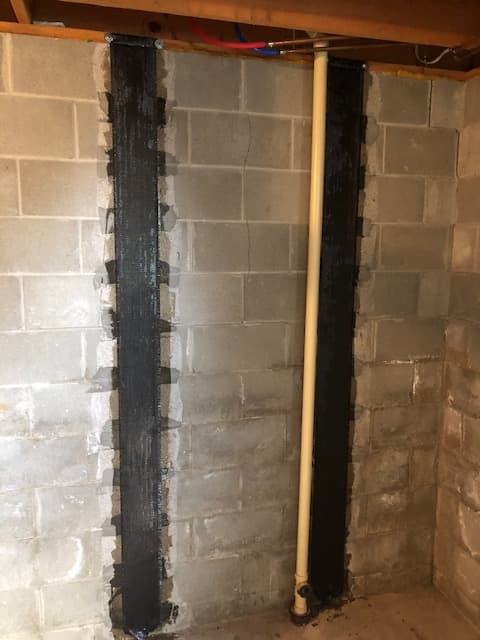 Carbon fiber reinforcement straps installed on a basement foundation wall to repair cracks and bowing.