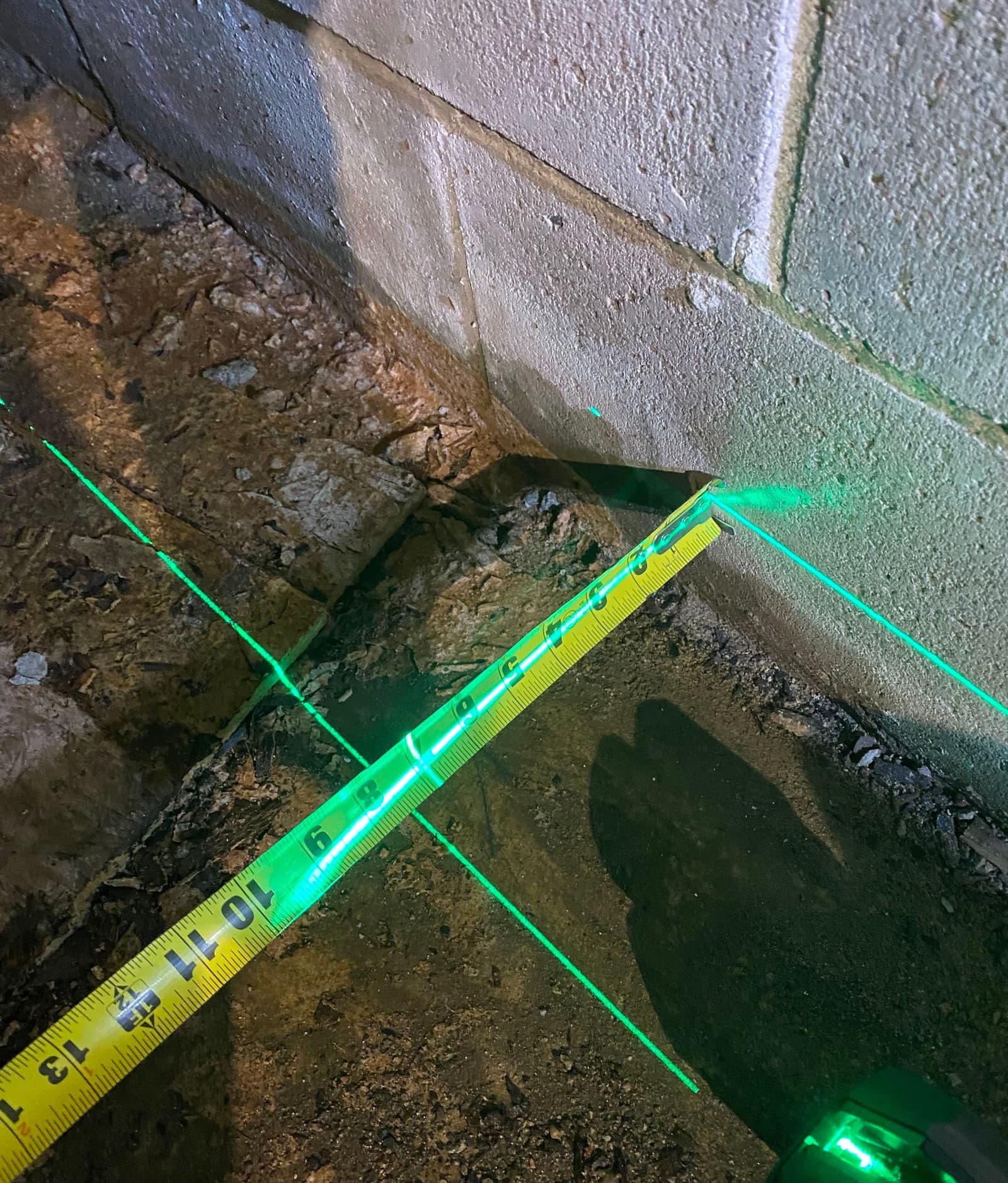 Epp Foundation Repair using a laser level and tape measure to assess foundation cracking in a basement in Lincoln, NE.