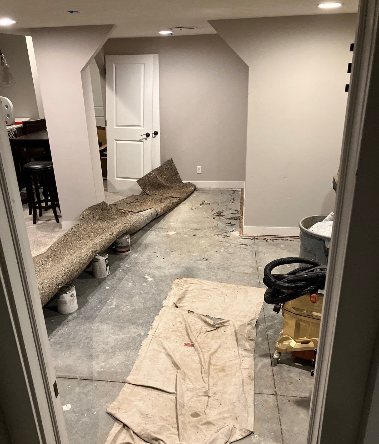 Epp Foundation Repair assessing a basement floor with rolled-up, discolored carpet, indicating possible mold growth and moist