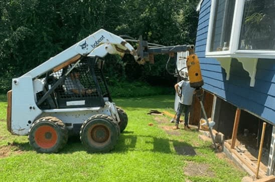 Epp Foundation Repair installing helical piers for a residential foundation using heavy machinery.