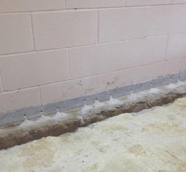 Epp Foundation Repair inspecting efflorescence and preparing for interior drainage system installation in a basement