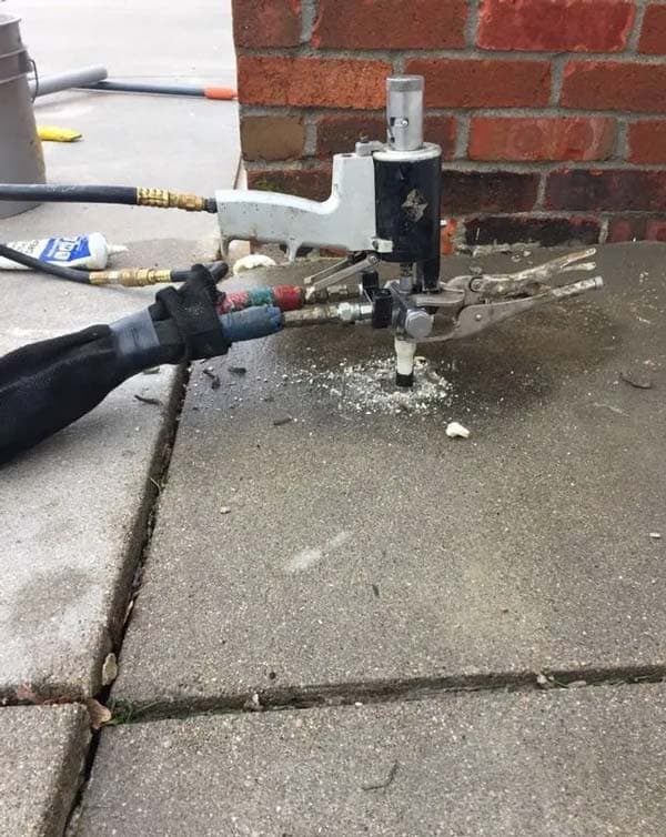 Epp Foundation Repair performing polyurethane foam injection for concrete leveling on a sidewalk.