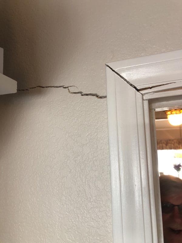 Epp Foundation Repair technician inspecting a large horizontal crack and a prominent gap around an interior door frame.
