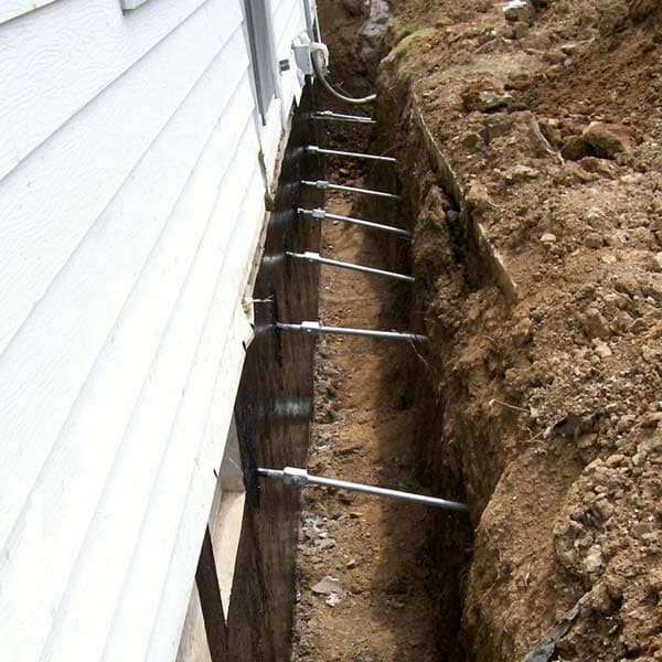 Epp Foundation Repair installing helical tieback anchors into an excavated residential foundation wall.
