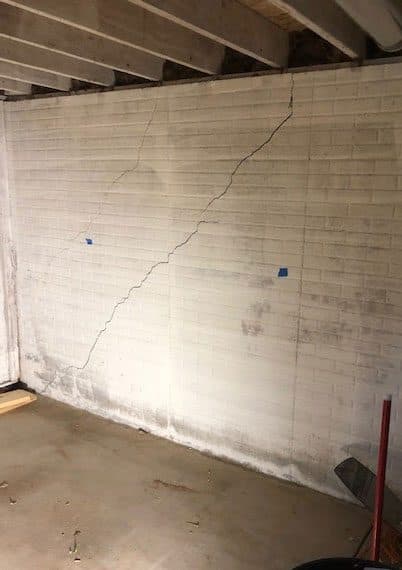 Epp Foundation Repair inspecting diagonal cracks and moisture staining on a block basement foundation wall.