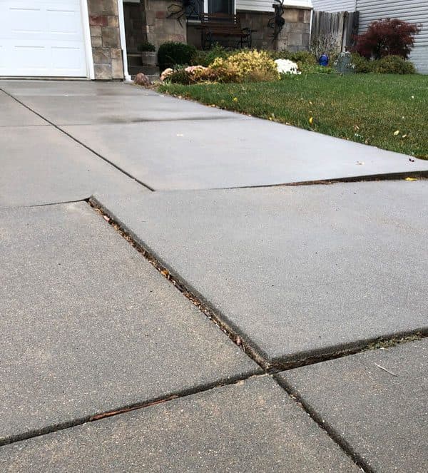 Epp Foundation Repair inspecting uneven concrete driveway slabs creating a dangerous trip hazard.