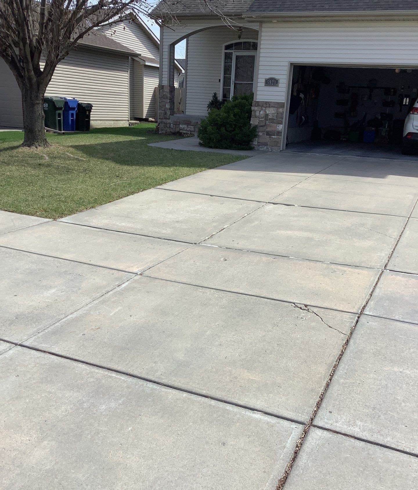 Epp Foundation Repair inspecting a cracked and uneven concrete driveway in Lincoln, NE.