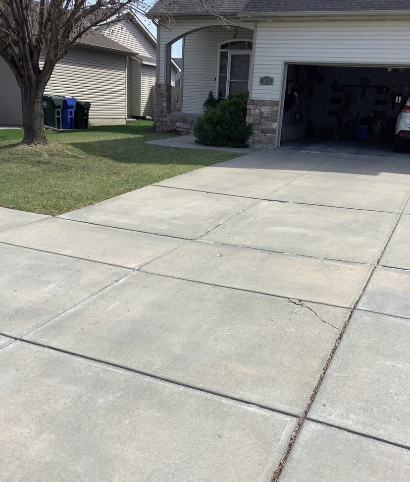 Epp Foundation Repair inspecting a cracked and uneven concrete driveway in Lincoln, NE.