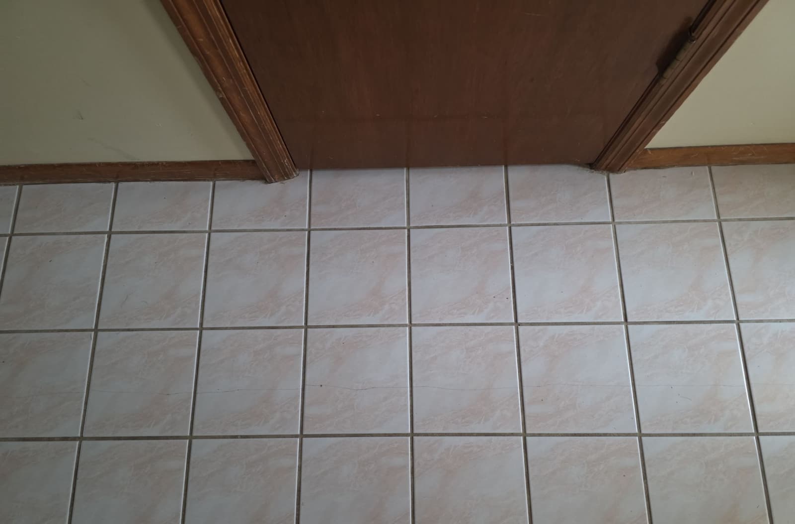 Epp Foundation Repair inspecting cracked floor tiles caused by foundation settling in Bellevue, NE.