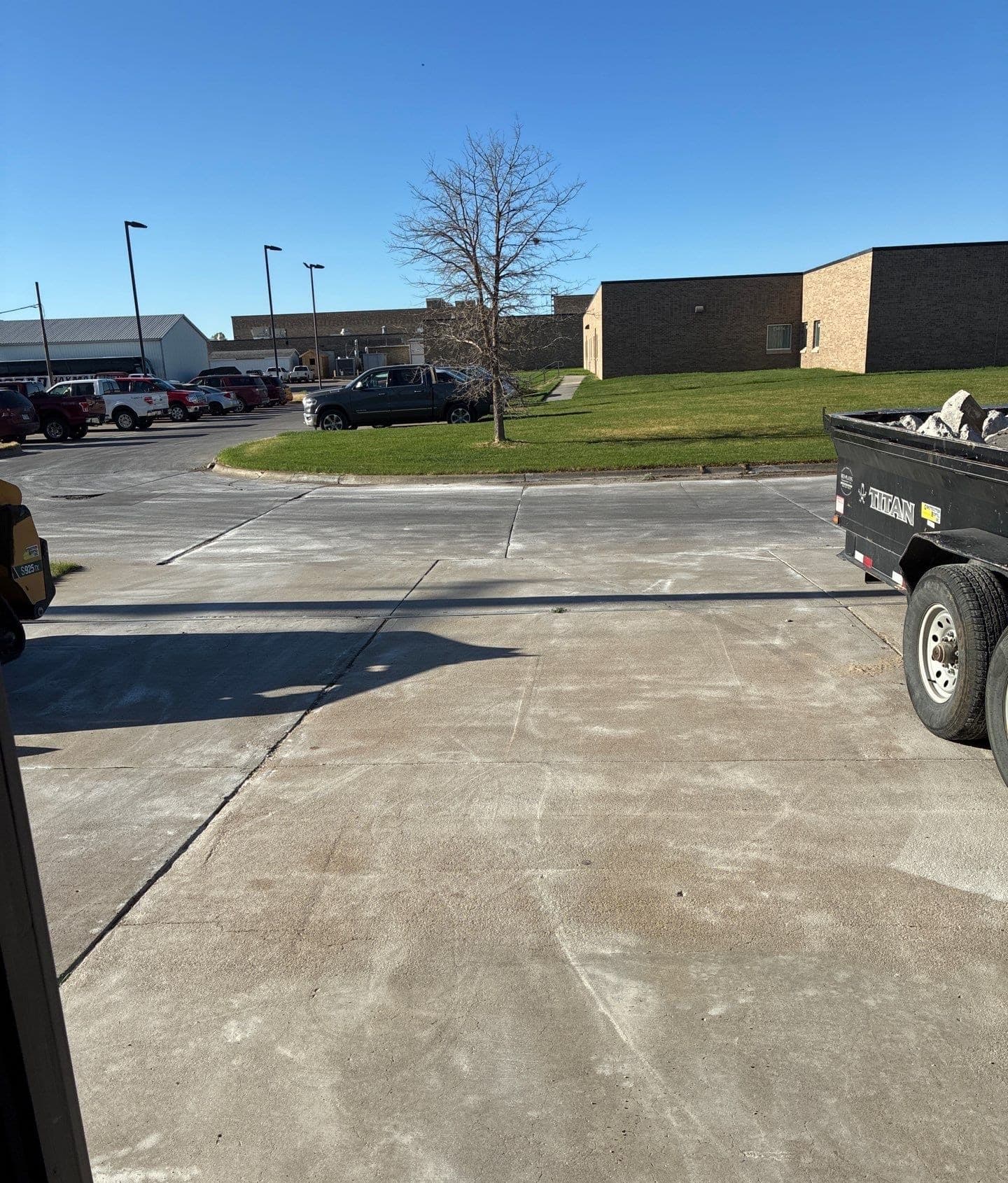 Epp Foundation Repair inspecting wide cracks in a commercial concrete parking lot with a dump trailer in Cozad, Nebraska.
