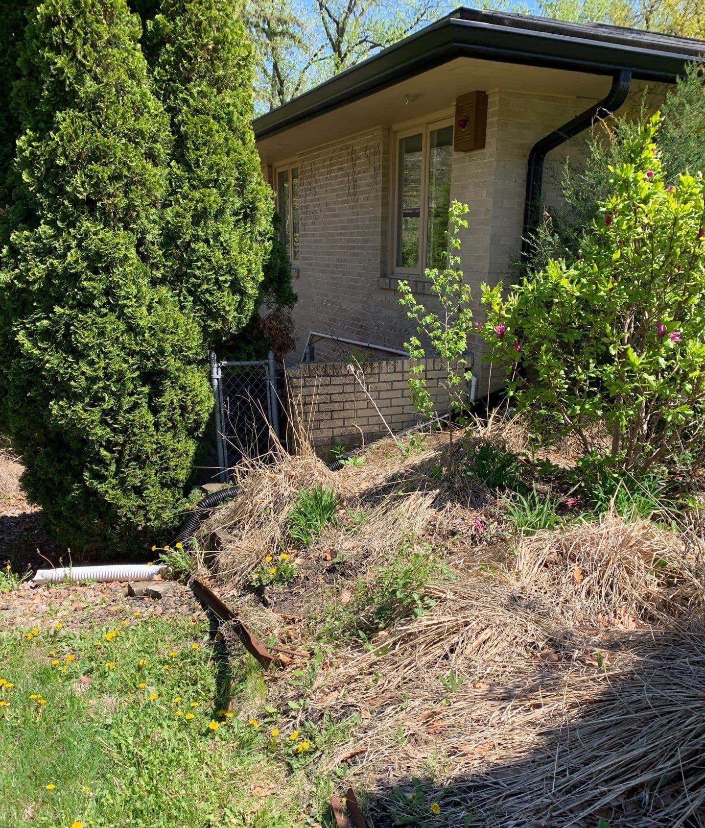 Epp Foundation Repair inspecting a crawl space access well with exterior drainage and downspout at a house foundation in Des 