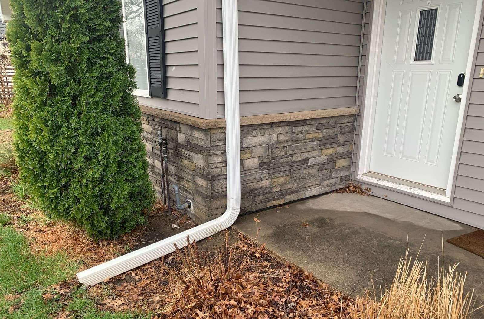 Epp Foundation Repair assessing exterior drainage near a home's foundation and concrete patio in Omaha, Nebraska.
