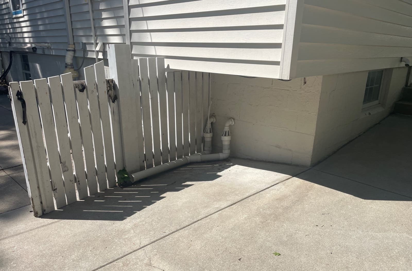 Epp Foundation Repair inspecting cracked concrete slab and exterior drainage pipes near a foundation in Lincoln, NE.