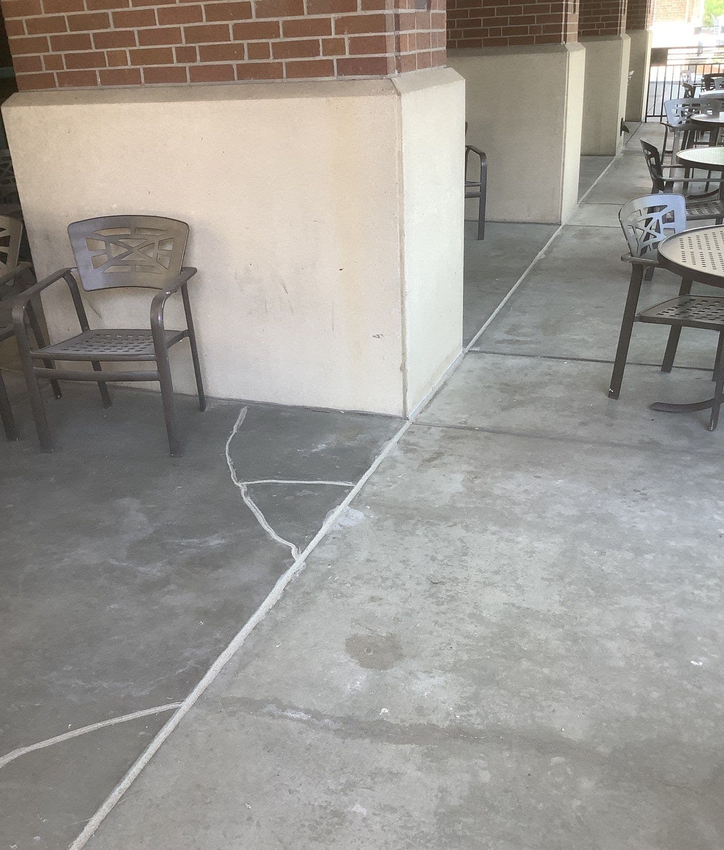 Epp Foundation Repair inspecting cracked concrete patio with visible repairs in Lincoln, Nebraska.