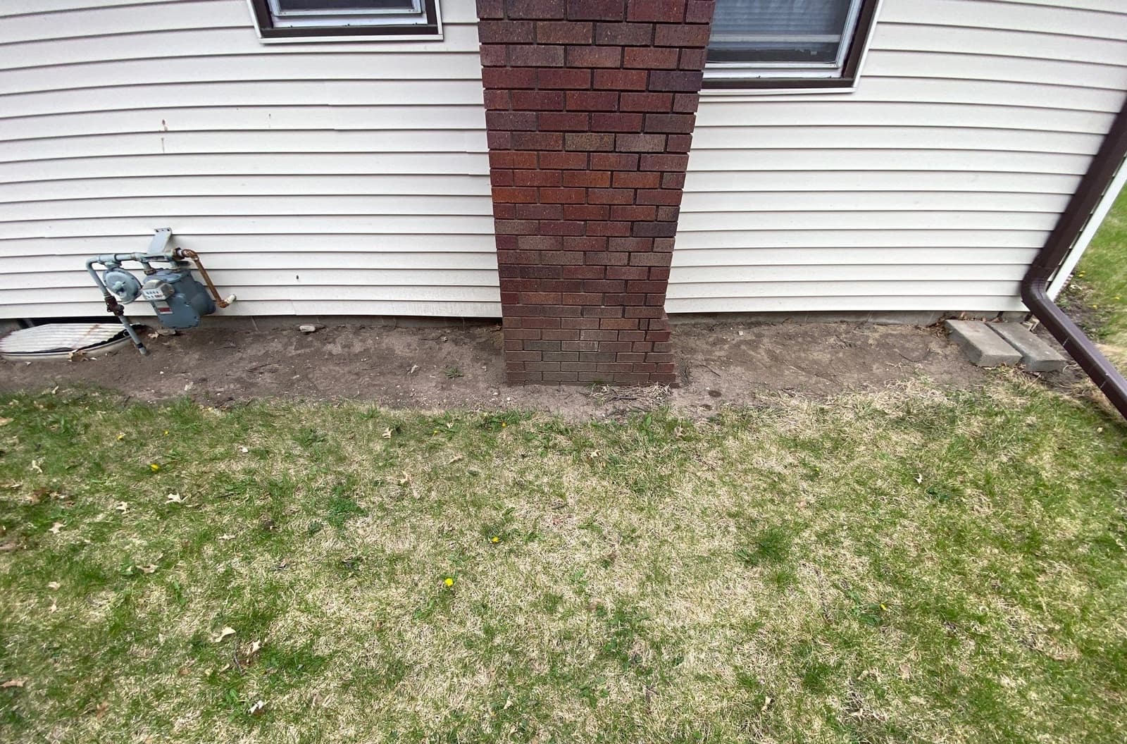 Epp Foundation Repair inspecting an exterior bowing brick chimney and exposed foundation with a leaning gas meter in Seward,