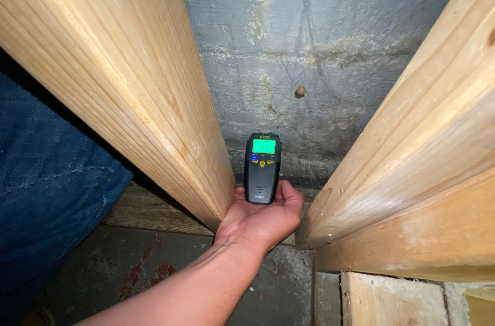 Epp Foundation Repair technician inspecting a crawl space wall for moisture and potential mold with a moisture meter in Linco