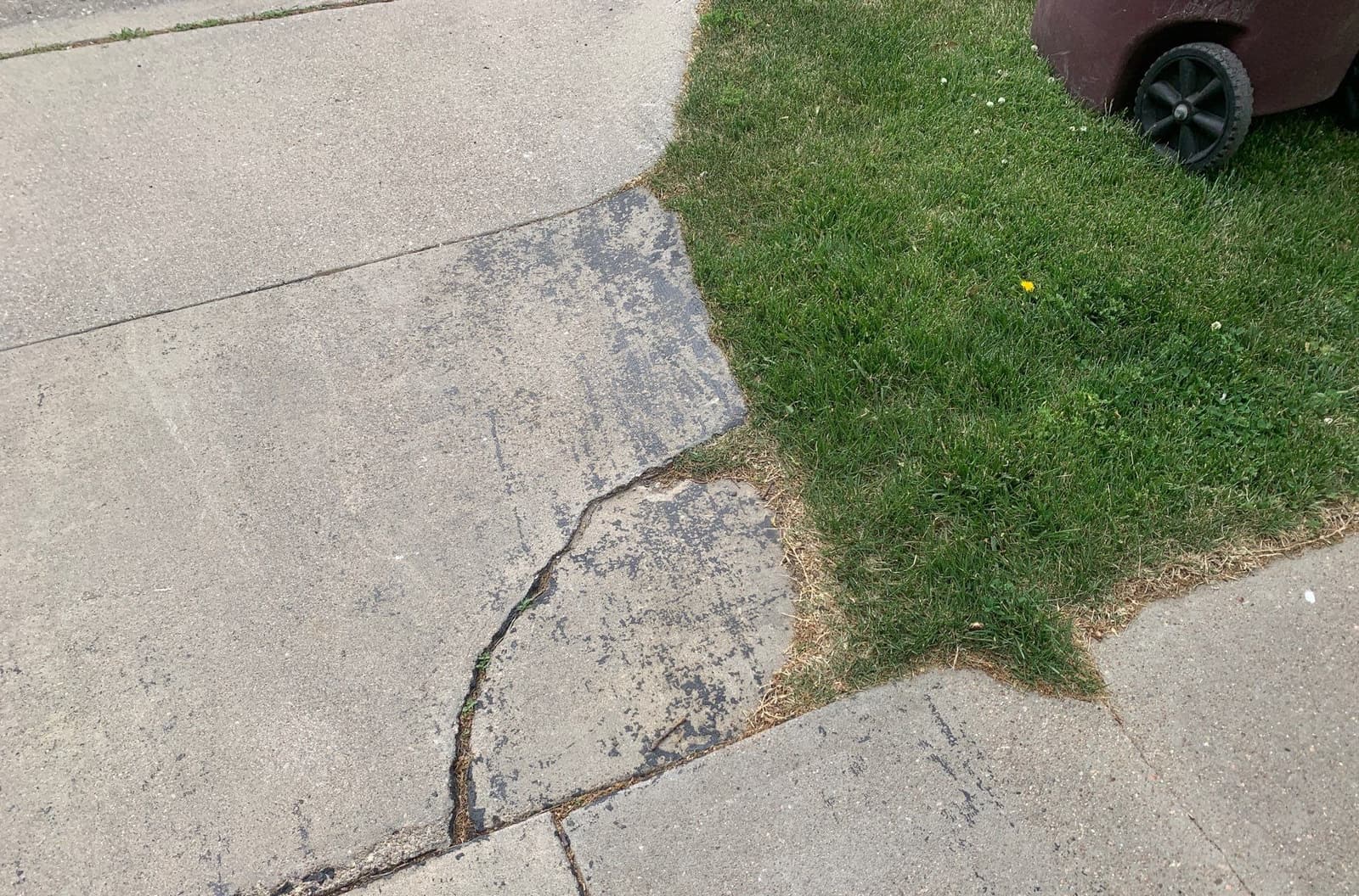 Epp Foundation Repair inspecting cracks in concrete sidewalk slabs in Lincoln, NE, indicating settlement.