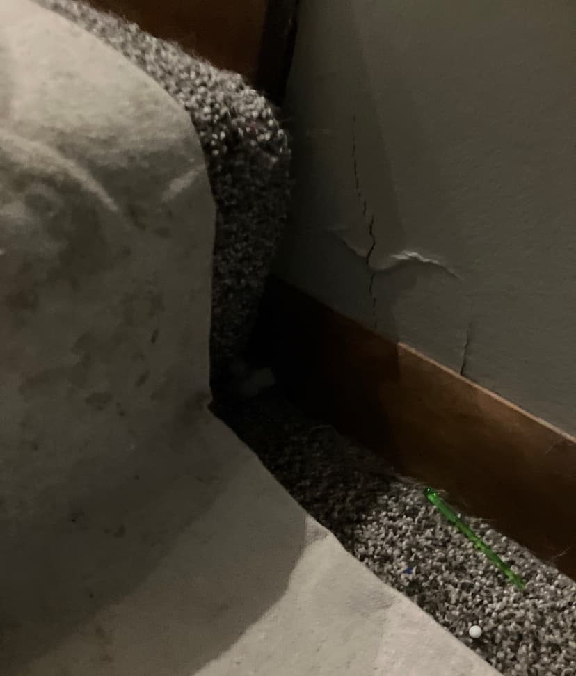 Epp Foundation Repair inspecting severe vertical wall cracks and peeling paint on an interior wall in Lincoln, Nebraska.