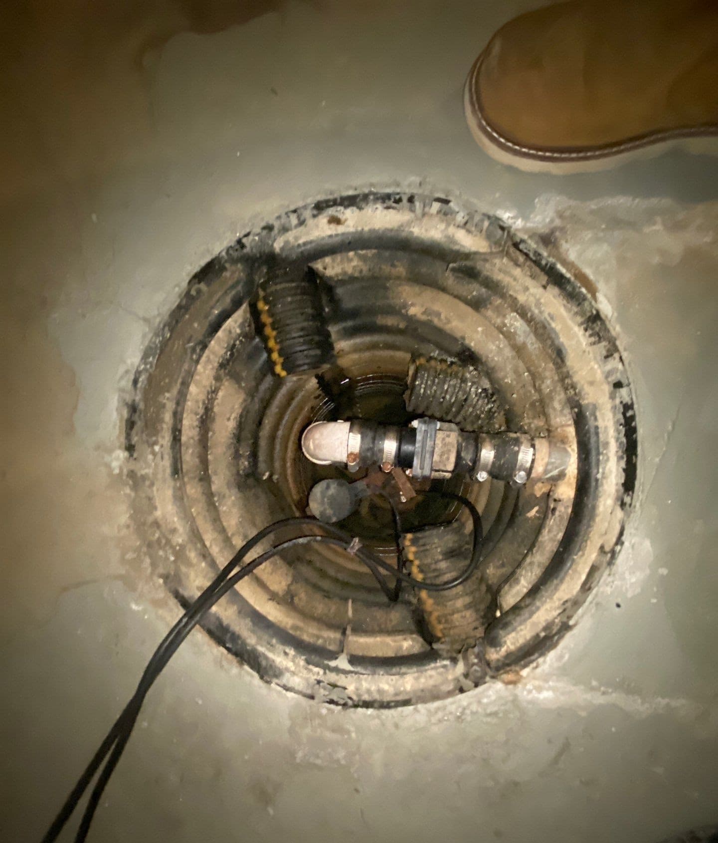 Epp Foundation Repair inspecting a sump pump in a flooded basement pit, addressing basement flooding and water damage in Omah
