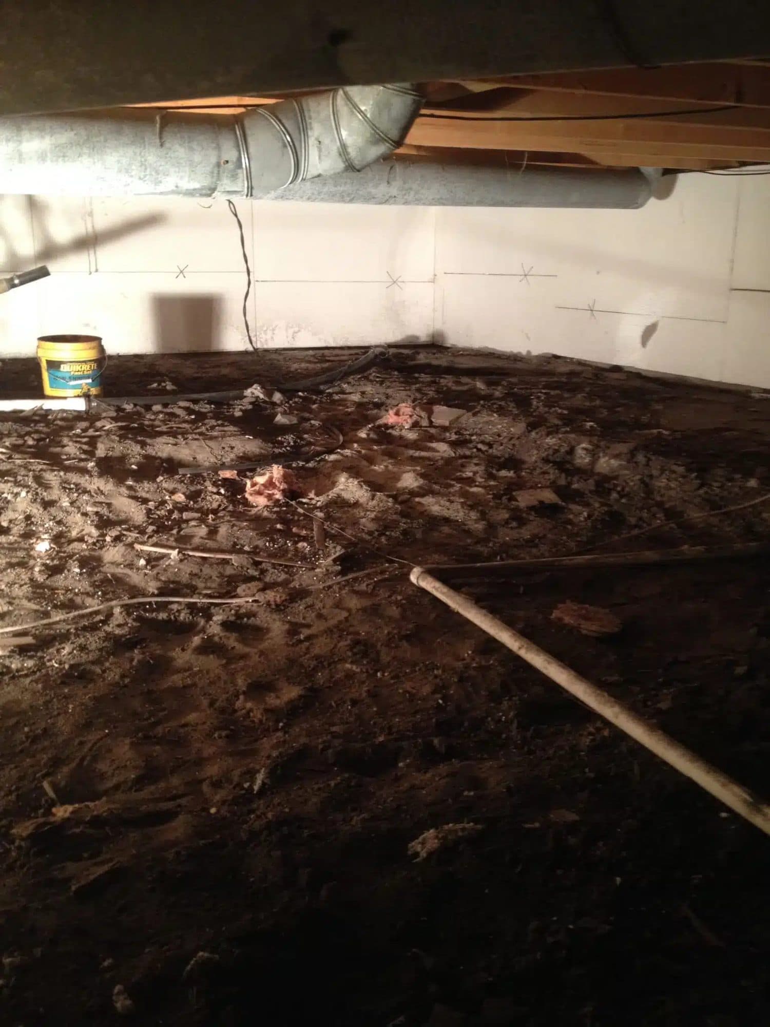 Epp Foundation Repair crew working in a dirty crawl space with exposed dirt floor and scattered debris.