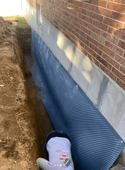 Epp Foundation Repair installing an exterior waterproofing membrane on a brick foundation wall.