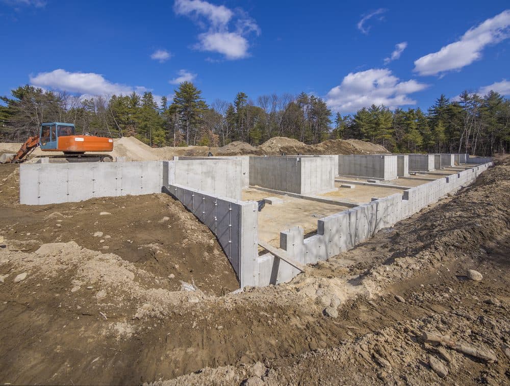 Epp Foundation Repair building a new concrete foundation for a residential structure, with an excavator on site.