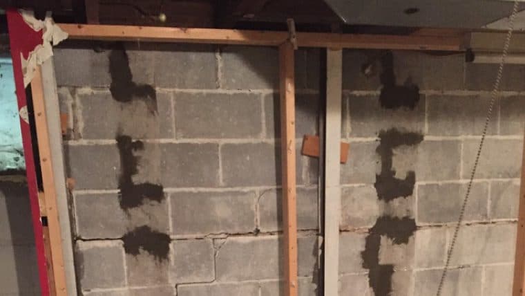 Epp Foundation Repair inspecting a bowing basement wall with multiple cracks and signs of prior injection repair.