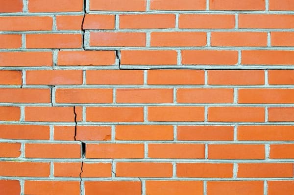 Epp Foundation Repair inspecting stair-step cracks in a brick exterior wall.