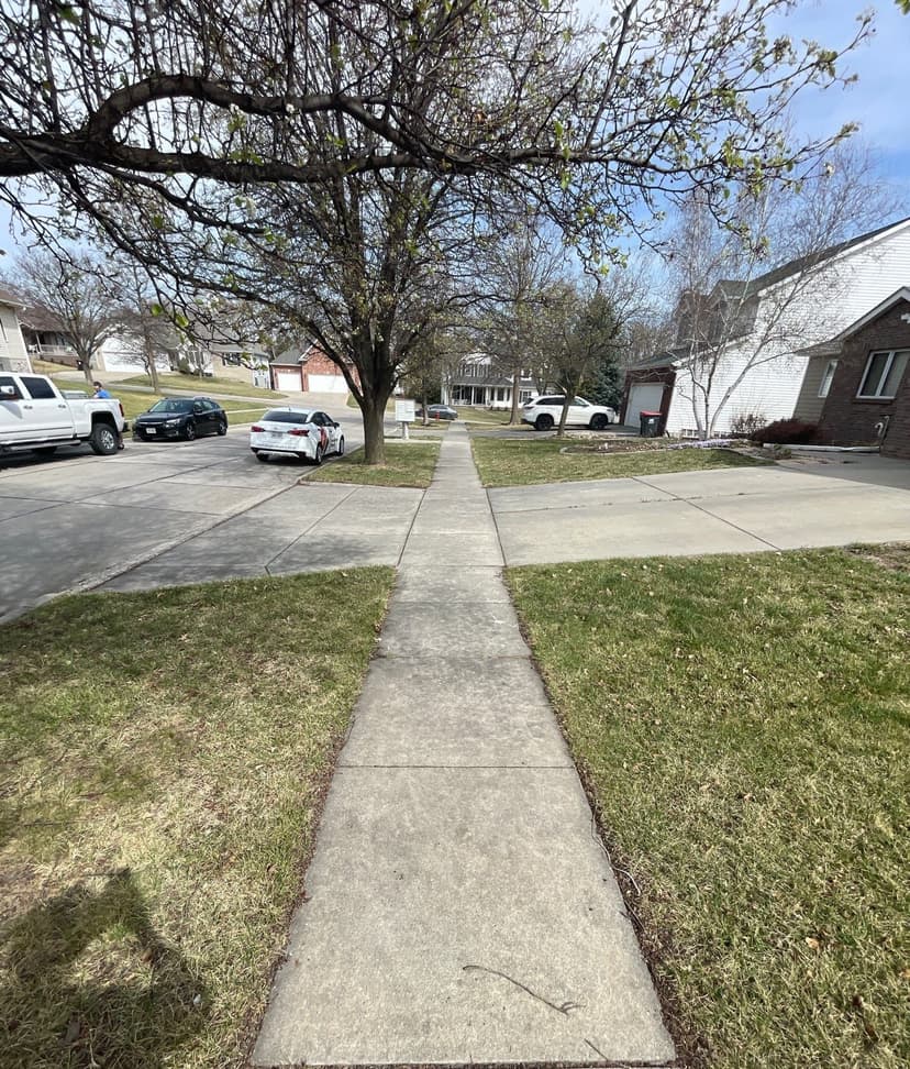 Epp Foundation Repair inspecting an uneven concrete sidewalk with trip hazards in a residential neighborhood in Lincoln, NE.