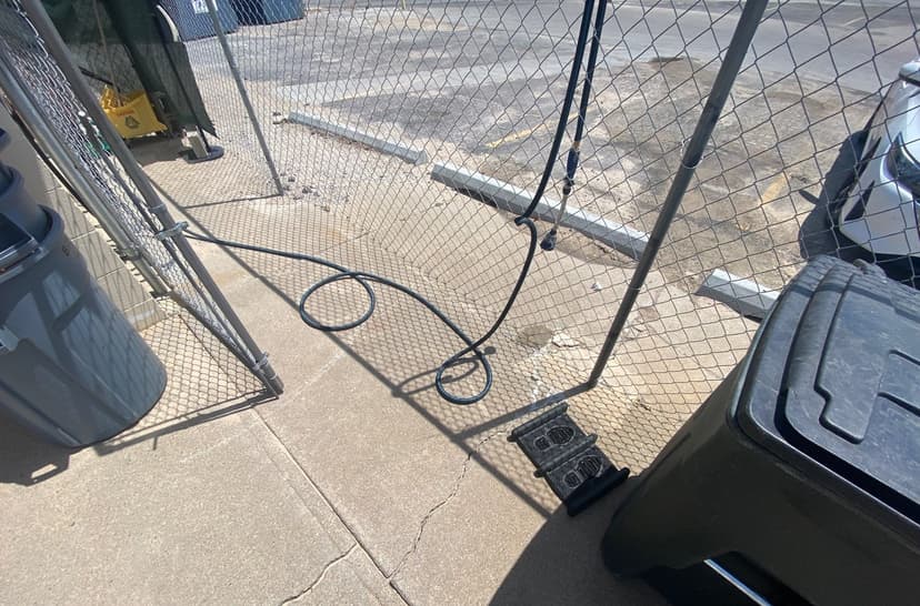 Epp Foundation Repair inspecting cracks in a concrete sidewalk near a chain link fence in Omaha, NE.