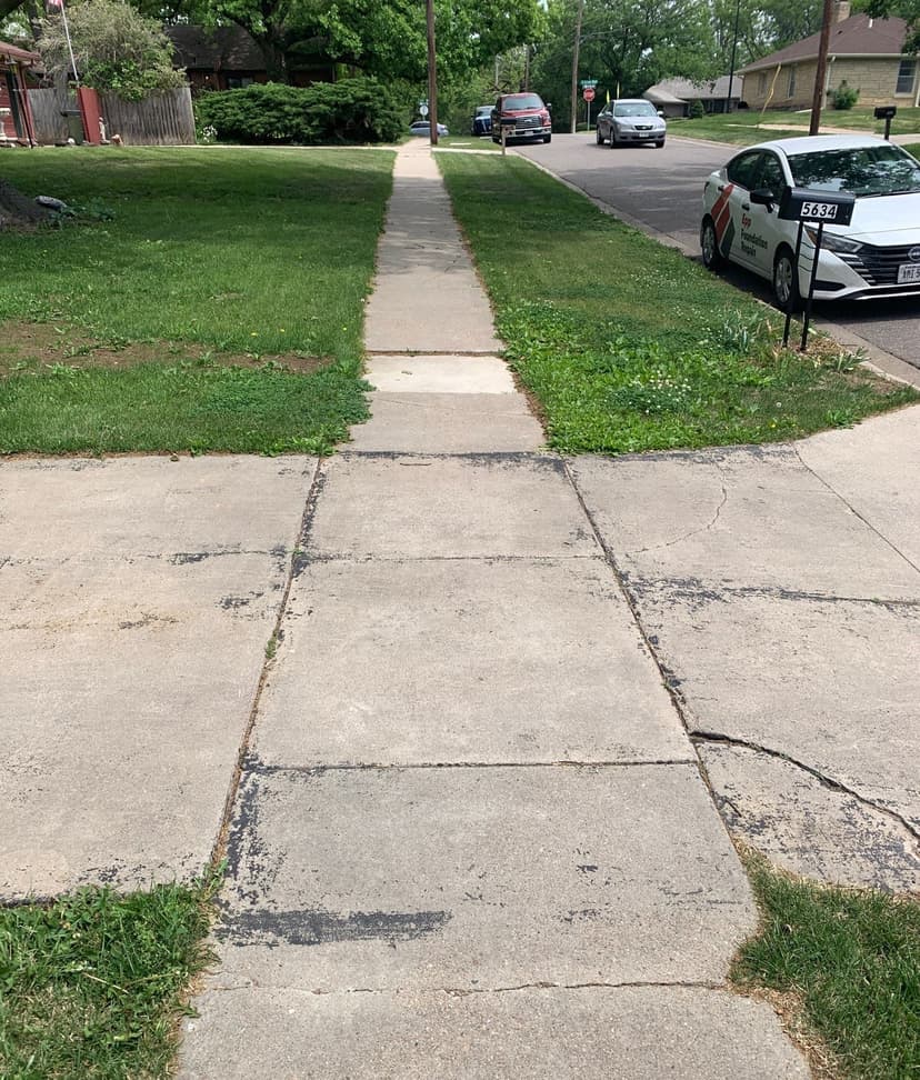 Epp Foundation Repair inspecting cracked and uneven residential concrete sidewalk with a service vehicle in Lincoln, NE.